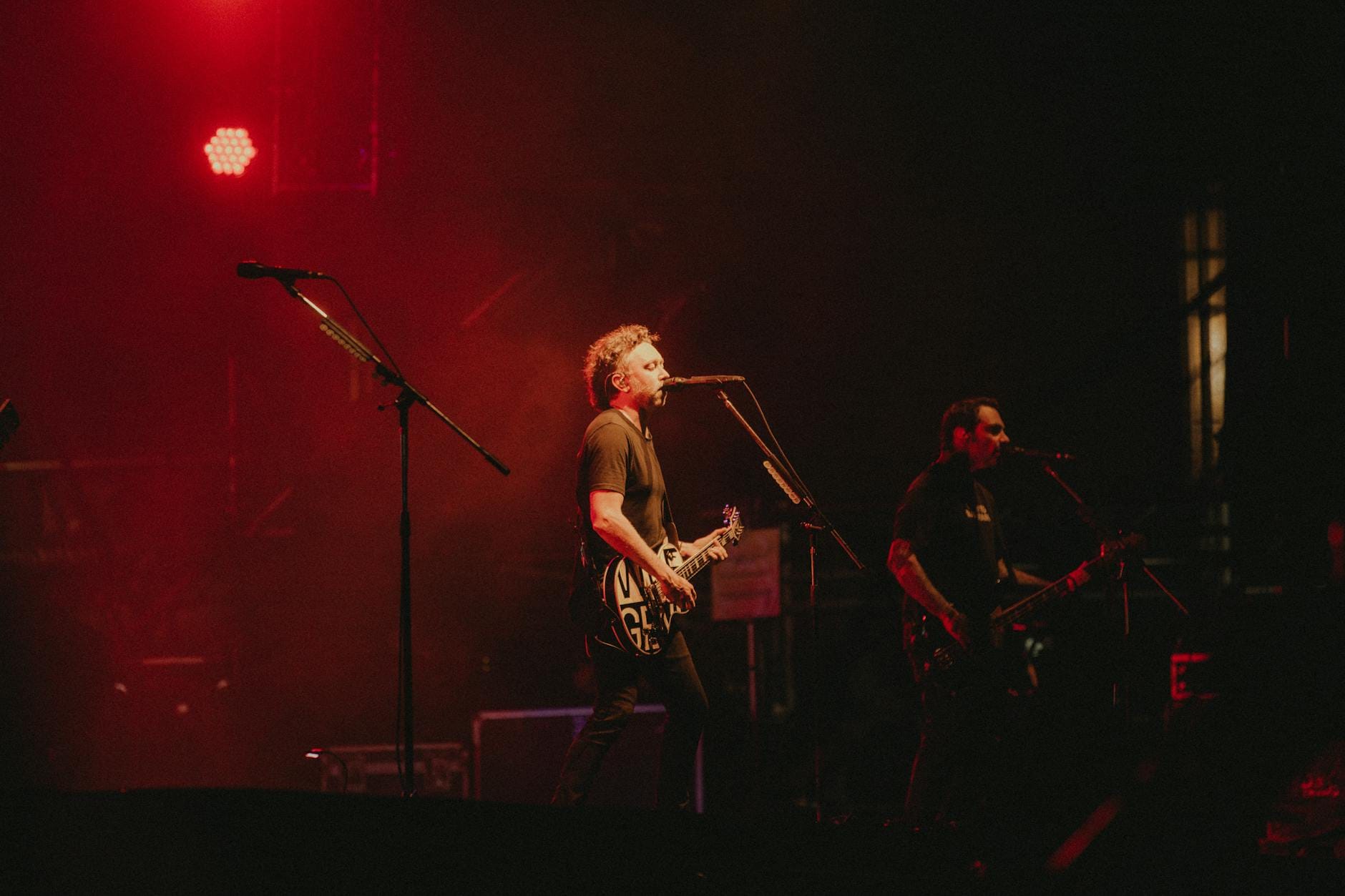 Rockowy zespół grający na żywo na scenie w czerwonym oświetleniu